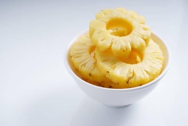 A peeled pineapple cut into pieces in a bowl, showing the safe flesh portion for rabbits