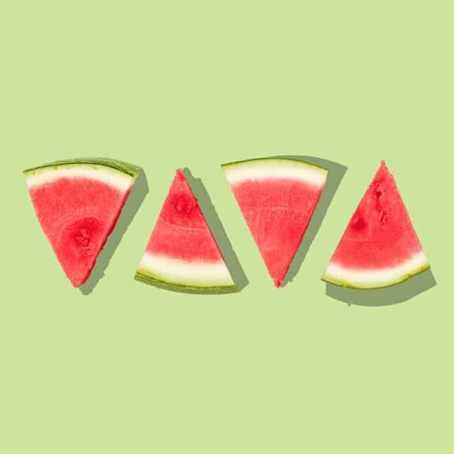 Four slices of fresh watermelon showing the red flesh and green rind